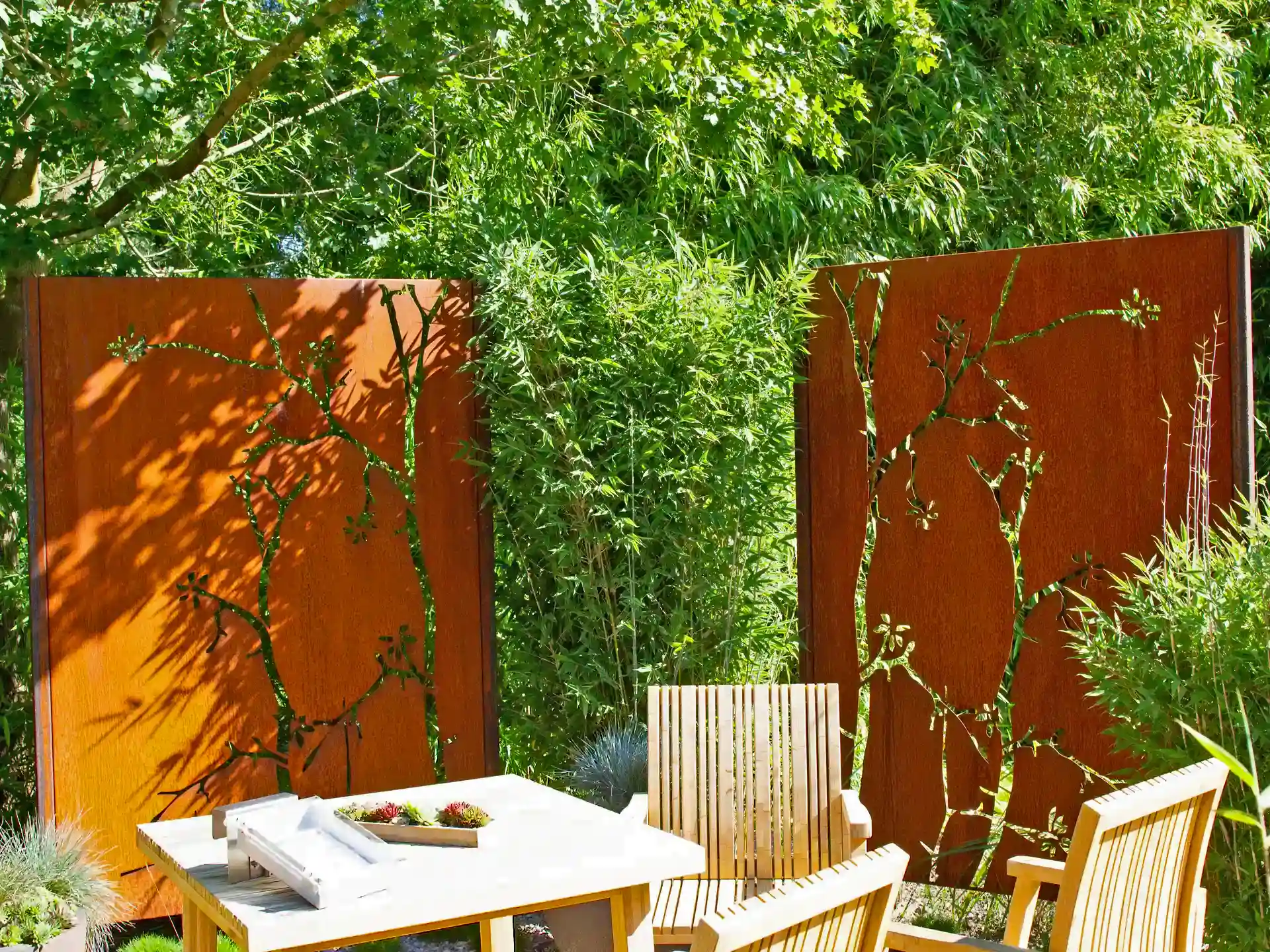 Bambus Fargesia 'Red Zebra' als stilvoller Sichtschutz an einer Terrasse mit Gartenmöbeln und Sichtschutzwänden - pflegeleichter Bambus mit Zierwert.
