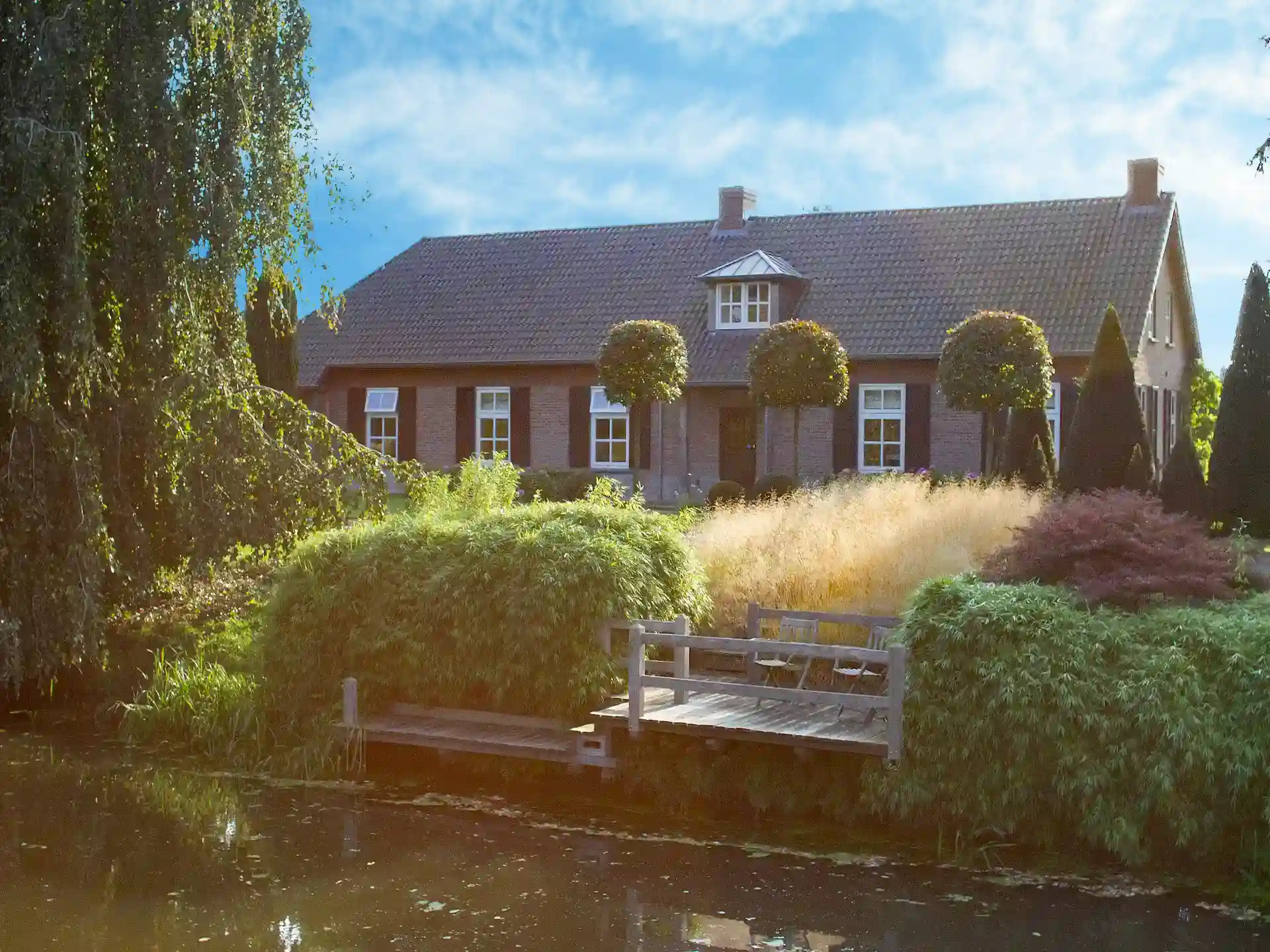 Gartenidylle mit Sitzbank und Fargesia Rufa Bambushecke am Wasserlauf.