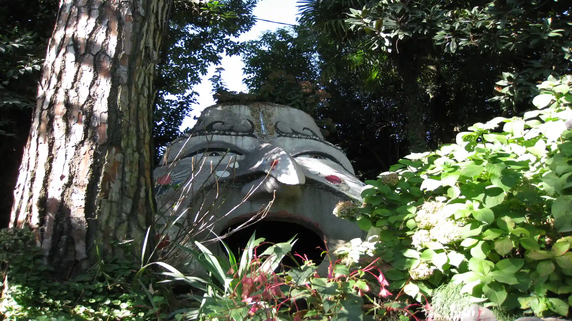 Steinskulptur mit großem, geöffneten Mund inmitten der Natur
