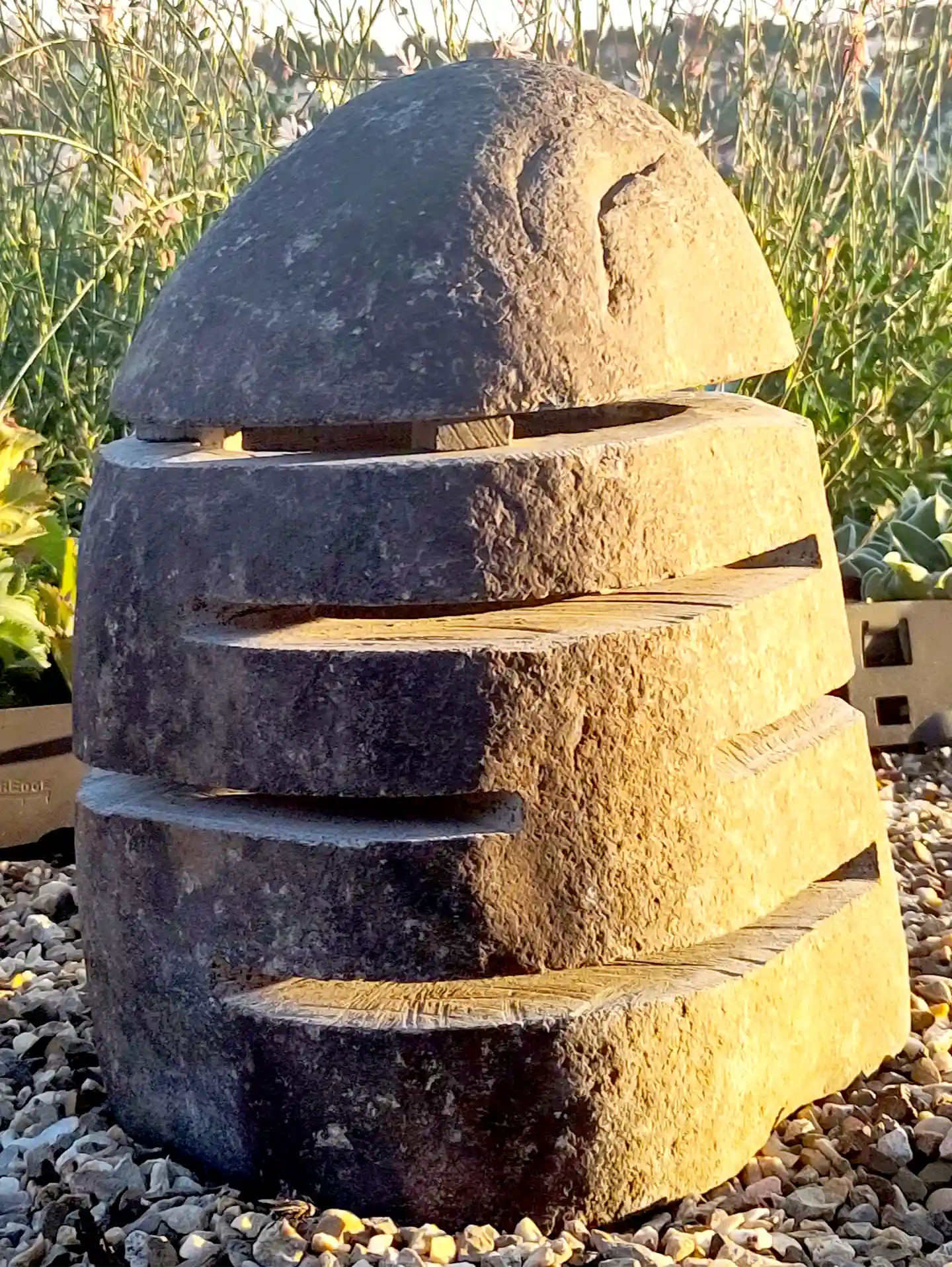 Steinlampe aus indonesischem Flussstein Steinlampe mit eingeschnittenen Lichtschnitzen aus Naturstein im Sonnenschein.