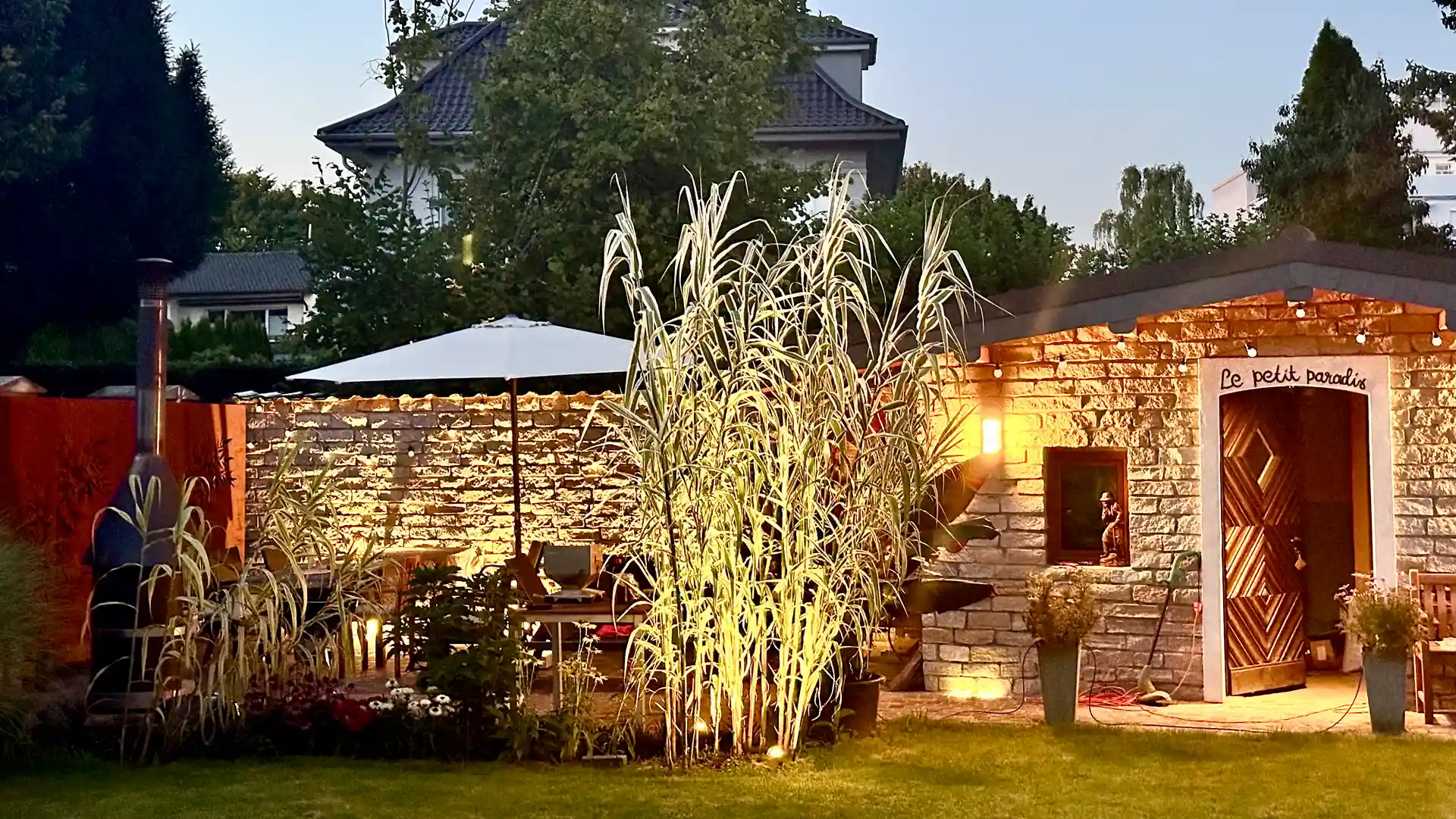 Arundo donax variegata vor einem Natursteinhaus mit Terrasse