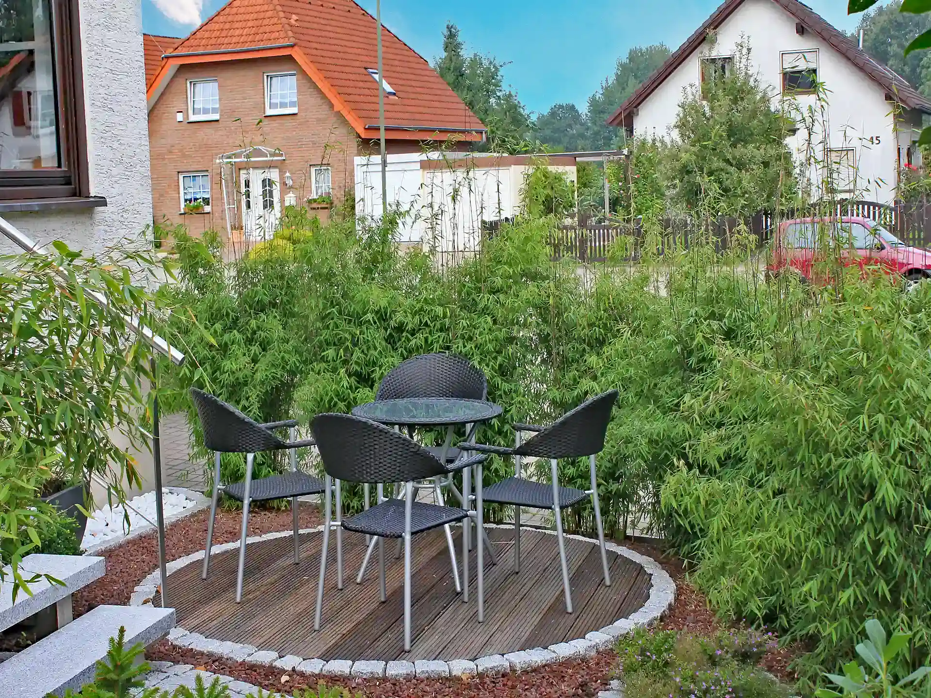 Roter Bambus Fargesia ‘Jiuzhaigou 1’ neben Terrasse mit Gartenmöbeln – pflegeleicht und elegant als natürliche Abgrenzung.